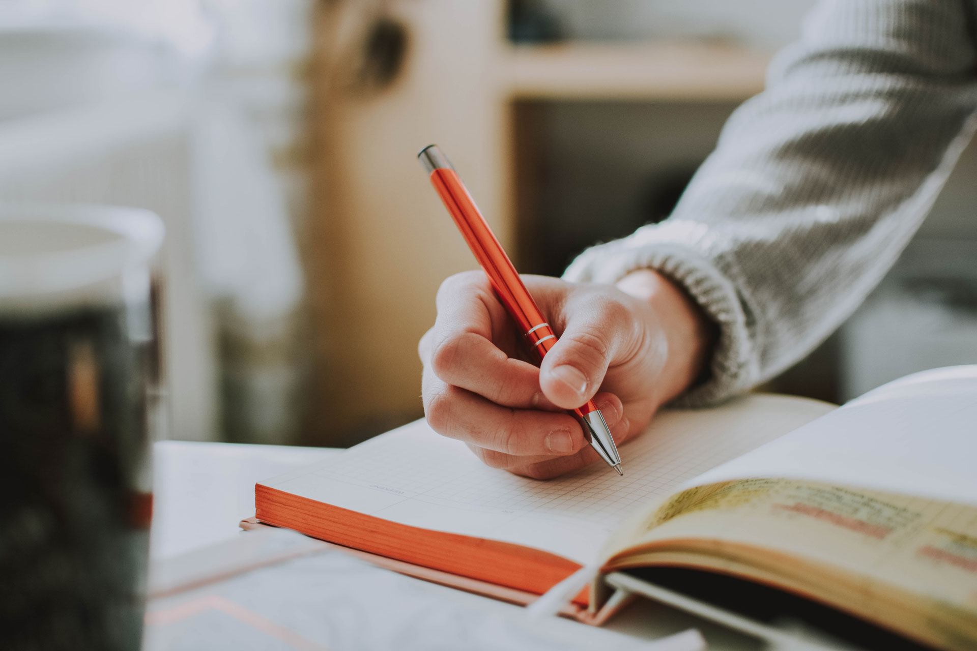 Persoon schrijft met een pen in een notitieboek.